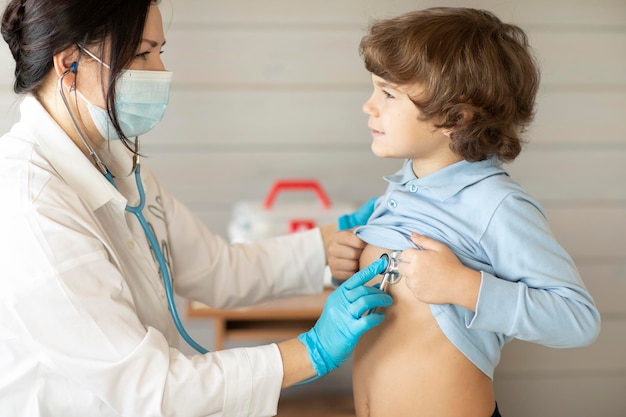 A boy in the clinic at the therapist's doctor on examination the doctor listens to the lungs