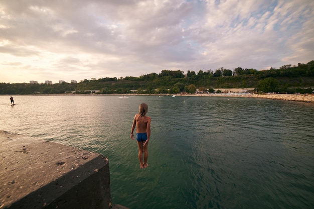 Boy dives into the sea from a pier Hot summer day