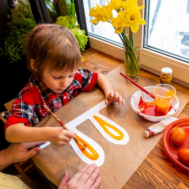 Boy drawing the ears of a handmade Easter bunny made of cardboard Preparation for the celebration of the Easter holiday