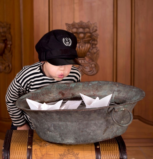 The boy dreams of becoming a sailor A child launches paper boats in a bowl of water at home