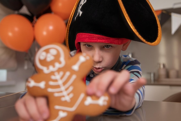 A boy dressed as a pirate eats skeletal gingerbread on Halloween and plays with cookies