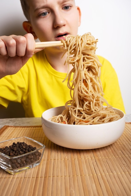 A boy eats Japanese noodles with chopsticks Selective focus on noodles an Asian dish