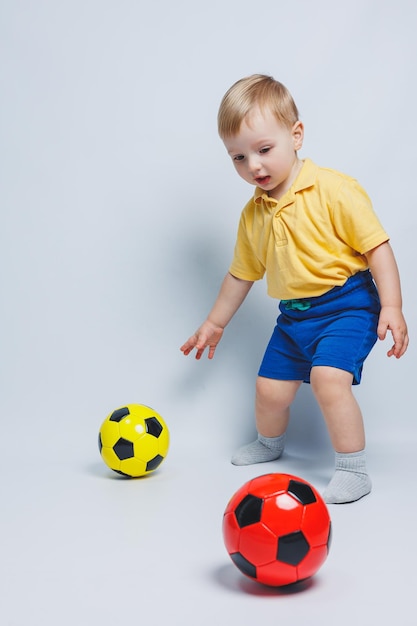 Boy fan holding a soccer ball in his hands isolated on a white background newbie child in football sport for kids Little athlete Yellow and blue football kit for kids