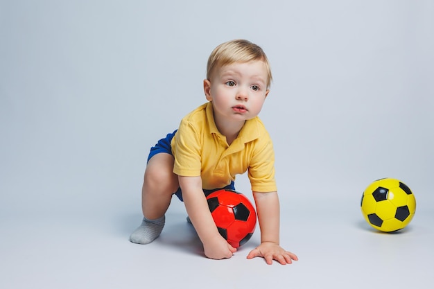 Boy fan holding a soccer ball in his hands isolated on a white background newbie child in football sport for kids Little athlete Yellow and blue football kit for kids