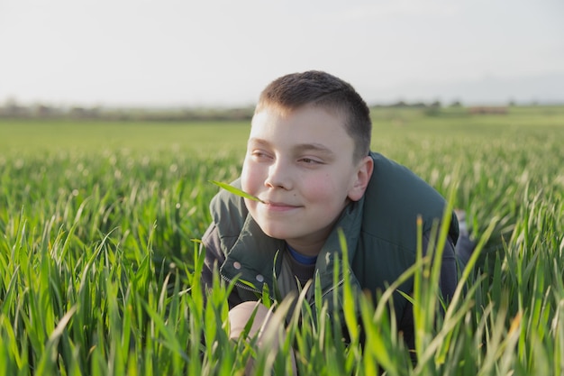 A boy in a field of grass with a stick in his mouth