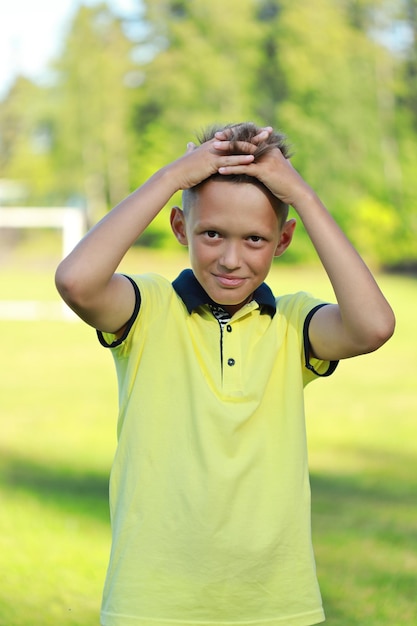 Boy football player stands in a yellow T-shirt stands on the football field.