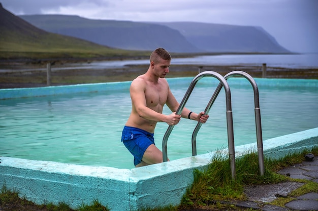 Boy gets out of the reykjafjardarlaug hot pool in the westfjords iceland