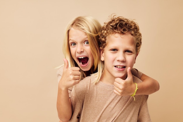 Boy and girl in beige tshirts posing for fun childhood unaltered