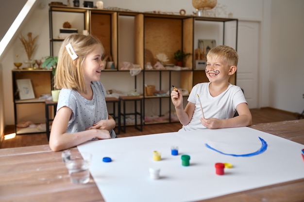 Boy and girl drawing with gouache on their faces