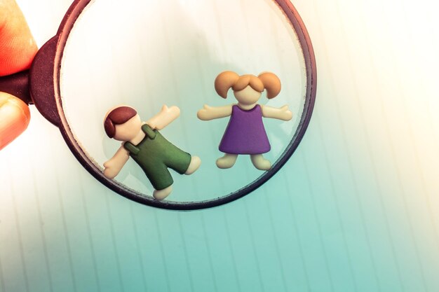 Boy and girl figurine on a magnifying glass