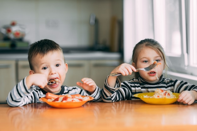 Boy and girl in the kitchen eating pasta