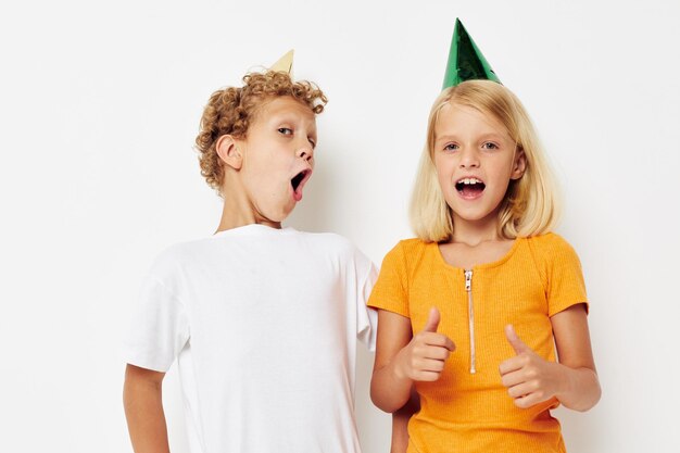 Boy and girl in multicolored caps birthday holiday emotion light background