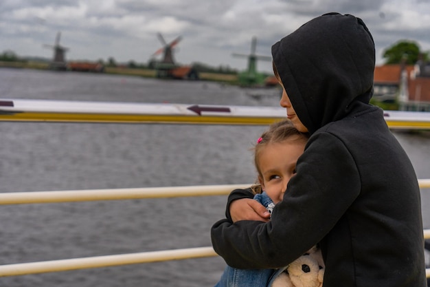 Boy and girl stands by Rural landscape with windmill in Zaanse Schans Holland Netherlands Authentic Zaandam mill Beautiful Netherland landscape