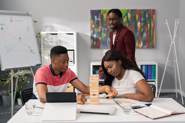 Boy and girl taking break from desk job building tower of wooden blocks having fun in office playing