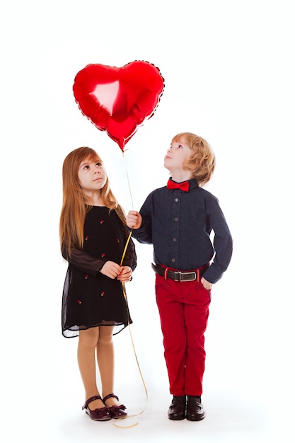 Boy and girl on a white background holding a balloon red heart