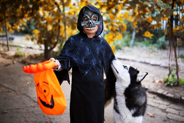 Boy in halloween costume with his pet husky dog holding a special candy bag