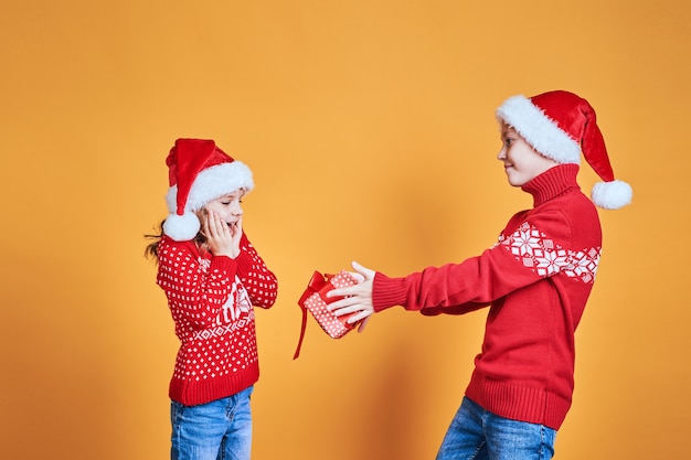 Boy handing Christmas present to surprised girl