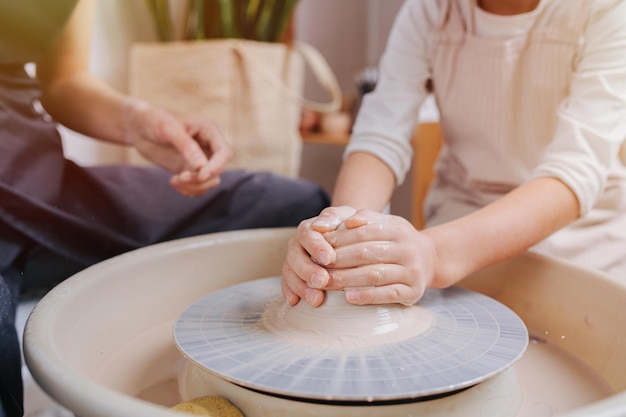 Boy hands shaping clay vase on a pottery wheel in a workshop