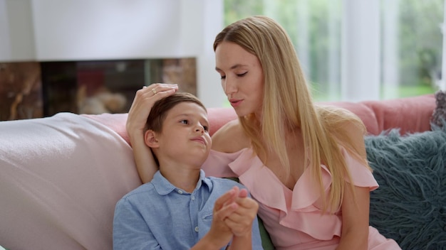 Boy having conversation with mother at home Mother and son sitting on sofa