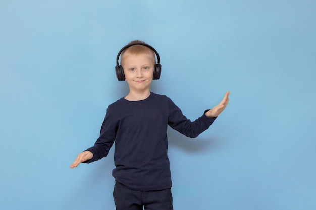 Boy in headphones listening to music and dancing on a blue background