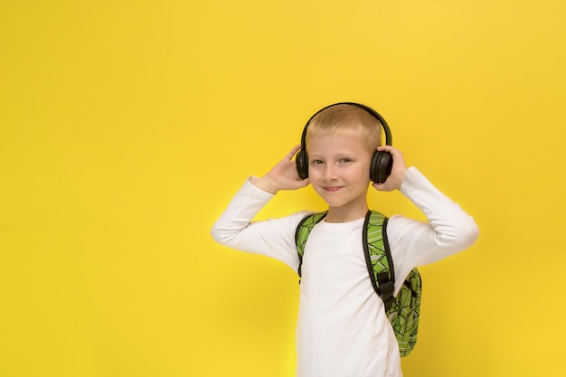 Boy in headphones with a backpack on a yellow background with copy space