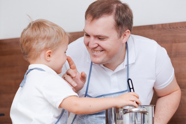 Boy and his father are preparing soup together in kitchen at home Having fun