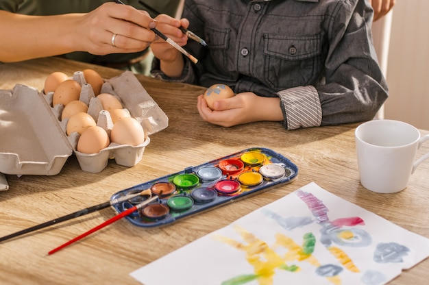 Boy and his mother painting eggs on Easter