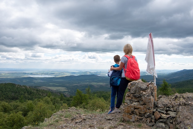 boy and his mother standing on top of the mountain