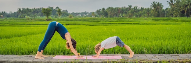 Boy and his yoga teacher doing yoga in a rice field banner long format