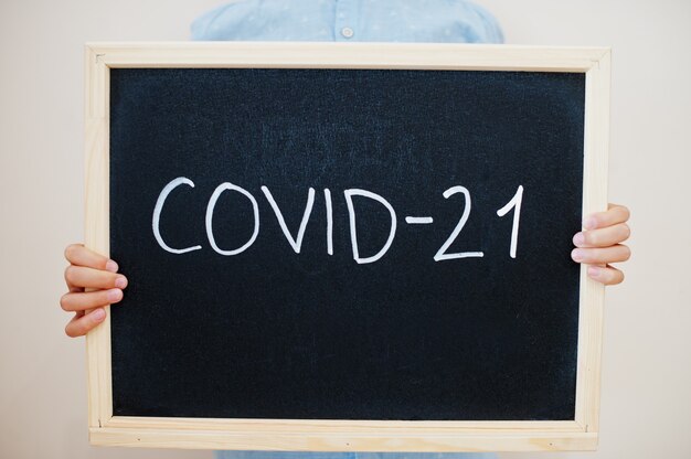 Boy hold inscription on the board with the text Covid-21