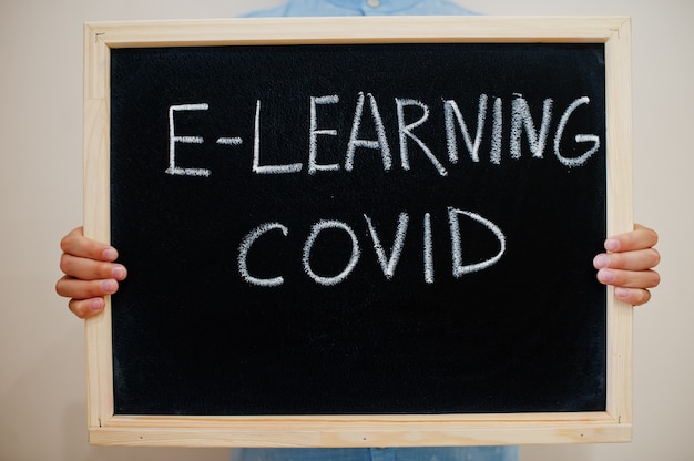 Boy hold inscription on the board with the text E-learning covid