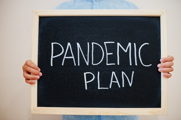 Boy hold inscription on the board with the text Pandemic plan