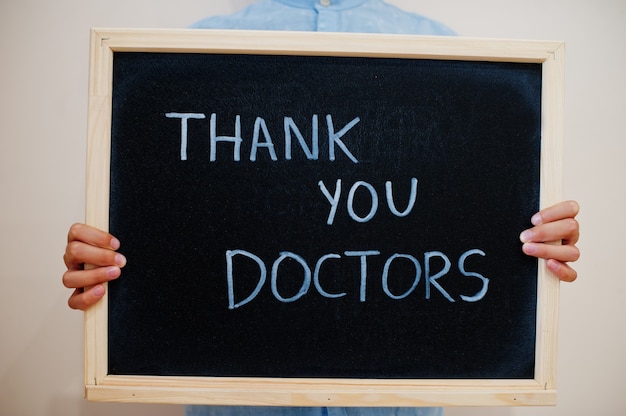 Boy hold inscription on the board with the text Thank you, doctors