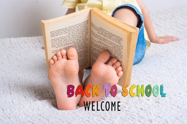 Boy holding book on feet as World book day concept