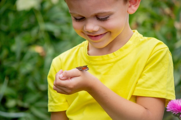 Photo boy holding a butterfly on his hand selective focus nature