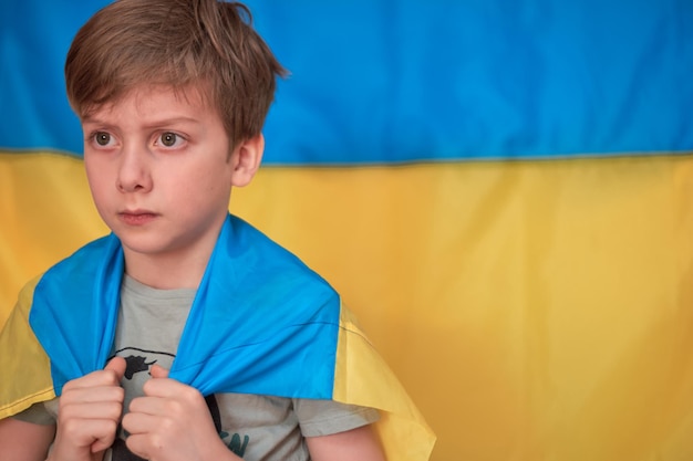 Boy holding in hands Ukrainian yellowblue flag Kids support Ukraine by showing heart