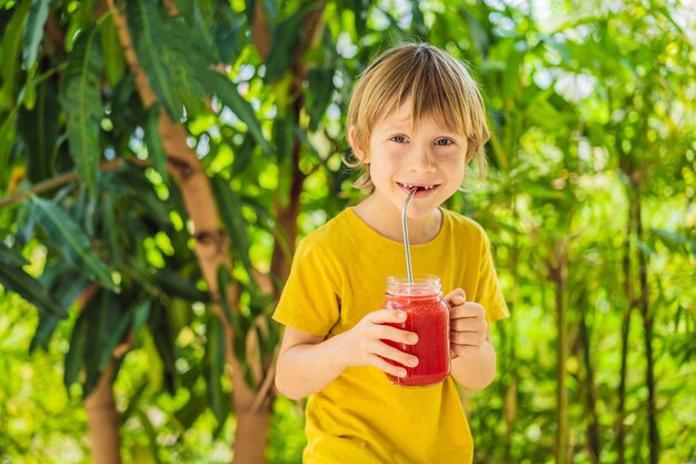 Boy holding healthy watermelon smoothie in mason jar