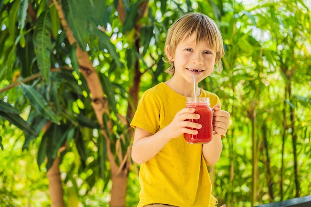 Boy holding healthy watermelon smoothie in mason jar