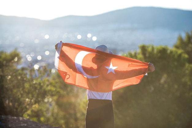 Boy holding Turkey flag against city Kid hand waving Turkish flag view from back copy space for text