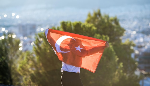 Boy holding Turkey flag against city Kid hand waving Turkish flag view from back copy space for text