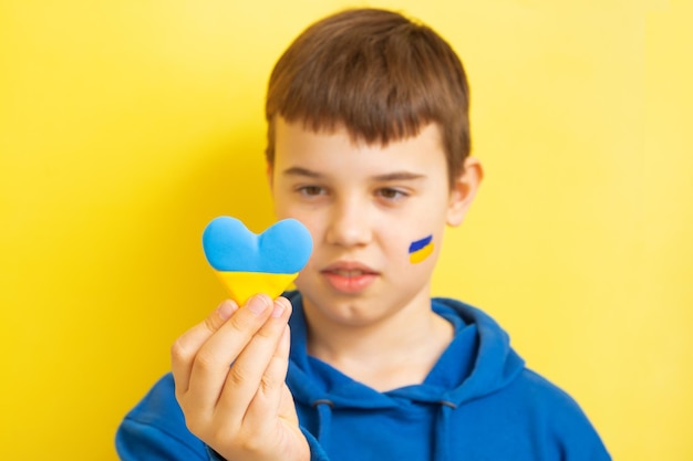 The boy holds a heart of yellow and blue color of the Ukrainian flag Love for Ukraine concept