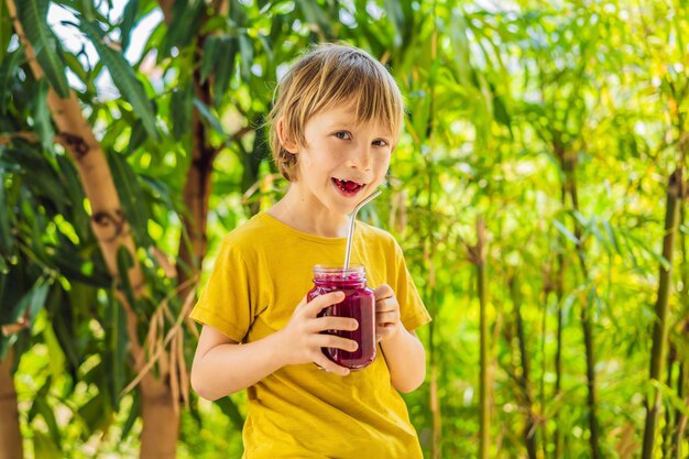 Boy holds smoothies from a dragon fruit with drinking straw