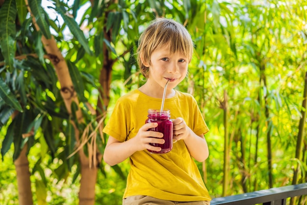 Boy holds smoothies from a dragon fruit with drinking straw