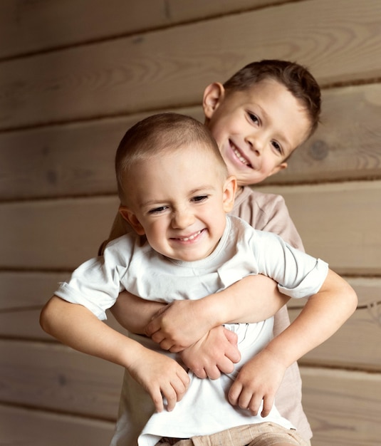 The boy hugs his little brother. The older brother holds the younger one in his arms