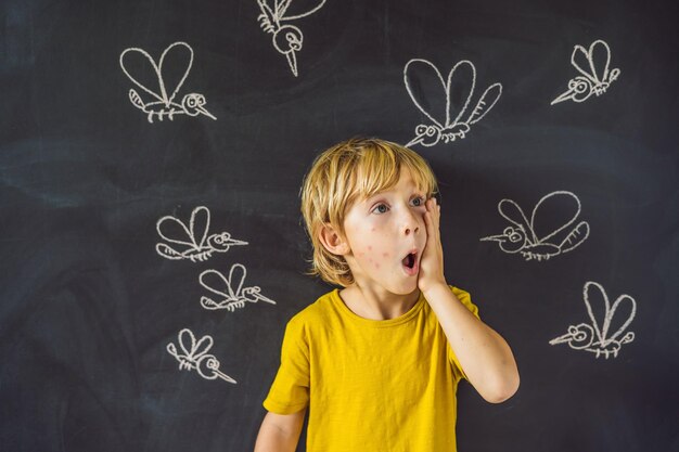 The boy is bitten by mosquitoes on a dark background On the blackboard with chalk painted mosquitoes