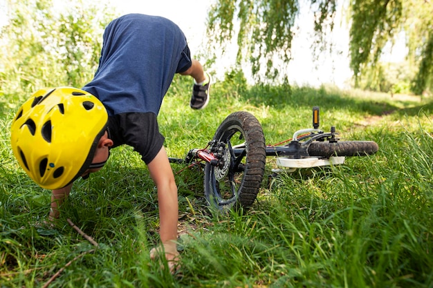 The boy is falling from the bicycle on the countryside