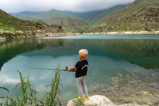 A boy is fishing on the mountain lake Gizhgit in KabardinoBalkaria Elbrus Region of Russia June 2021