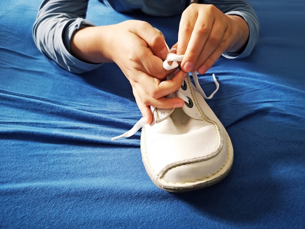 Boy is learning how to tie shoelaces