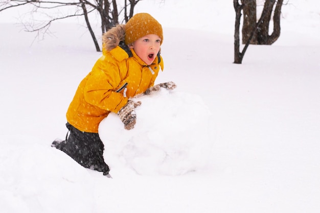 Boy is making snowman in park