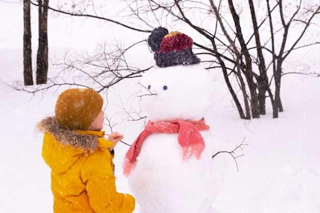 Boy is making snowman in park